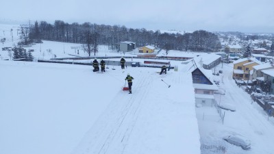 Mohla by se propadnout, proto hasiči odklízejí těžký sníh se střechy zimního stadionu v Poličce, místem projíždějte opatrně